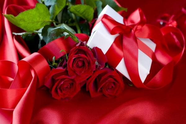 Caja de regalo junto a un ramo de rosas rojas