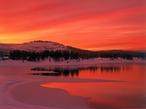 Postal: Puesta de sol rojiza sobre un paisaje nevado