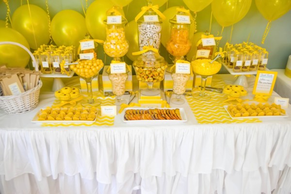 Mesa con caramelos y globos amarillos