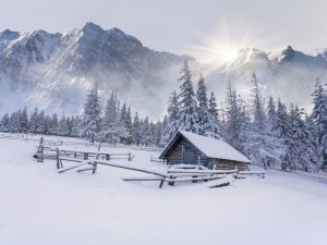 Postal: Cabaña cubierta de nieve recibiendo los rayos del sol