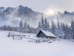 Cabaña cubierta de nieve recibiendo los rayos del sol