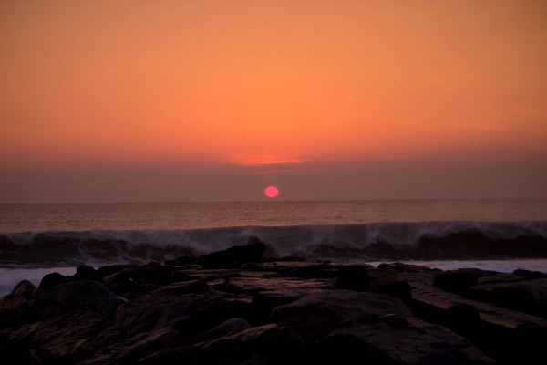 Vista del sol al anochecer en una playa rocosa