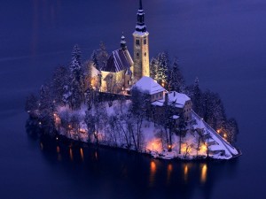 Postal: Iglesia iluminada en una isla cubierta de nieve