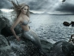 Sirena sentada en las rocas junto al mar