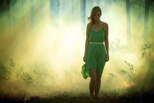 Joven caminando en el bosque con un vestido verde