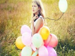 Una chica con varios globos en el campo