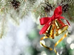 Campanitas doradas y un lazo rojo colgados en el árbol de Navidad