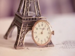 Reloj sin correa junto a una Torre Eiffel en miniatura