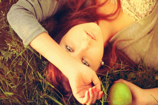 Una chica tumbada con una manzana en su mano