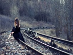 Mujer con zapatillas de ballet sentada en la vía de tren