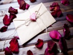 Una carta de amor junto a pétalos de rosas para San Valentín