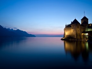 Postal: Un castillo junto al agua visto al amanecer