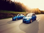 Dos coches Subaru de color azul en la misma carretera