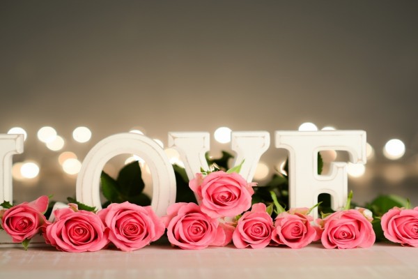 Rosas color rosa junto a la palabra "Love"
