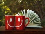 Dos tazas sonrientes junto a un libro