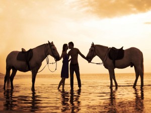 Pareja en una playa besándose tras un paseo a caballo
