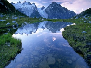 Montañas reflejadas en las aguas transparentes de un pequeño lago