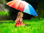 Niña con un paraguas de colores en un verde prado