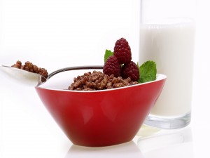 Un vaso de leche junto a un tazón con cereales
