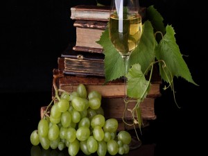 Una mesa con libros y buen vino de uva blanca