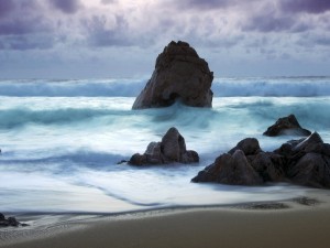 Postal: Olas entre las rocas de una playa