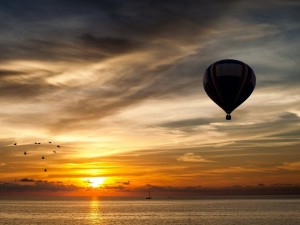 Postal: Globo volando sobre el mar al amanecer