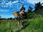 Chica paseando en bicicleta sobre la hierba fresca