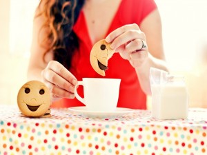 Postal: Chica comiendo unas galletas de caritas sonrientes