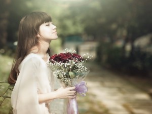 Postal: Mujer aspirando el aroma de las flores