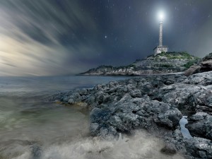 Postal: Faro iluminando una noche estrellada