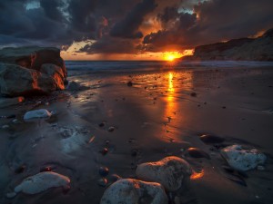 El sol del amanecer reflejado en la arena de una playa