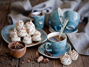 Postal: Taza de café especiado junto a pequeños merengues