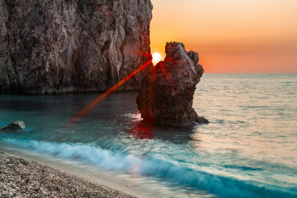 Rayos de sol entre dos rocas marinas