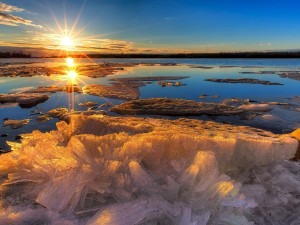 Los rayos dorados del sol iluminan un lago helado al amanecer