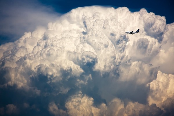 Un avión volando junto a una masa nubes