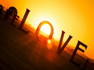Postal: El sol detrás de grande letras que forman la palabra amor
