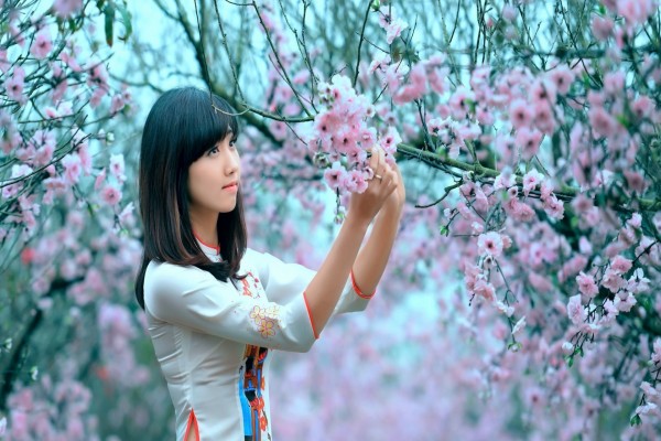 Chica observando las flores de un árbol