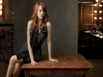La guapa actriz Emma Stone sentada en una mesa de madera