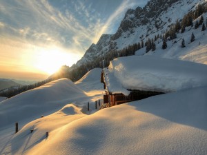 Los rayos del sol iluminan una casa cubierta de nieve