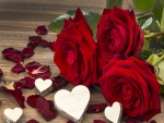 Corazones blancos tallados en madera junto a unas rosas rojas