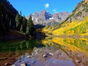 Postal: Árboles otoñales en las montañas reflejados en el lago