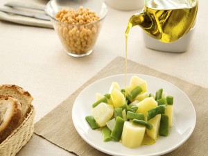 Aliñando con aceite de oliva unas ricas patatas con judías verdes