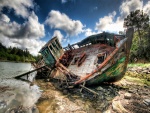 Viejo barco tumbado en la orilla de un río