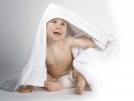 Bebé sonriendo bajo una toalla