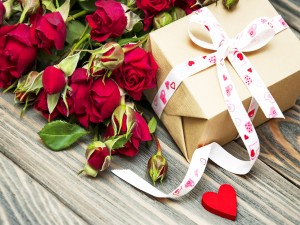 Ramo de rosas rojas y un regalo atado con una cinta