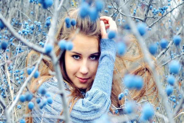 Chica hermosa entre unos matorrales con frutas de color azul