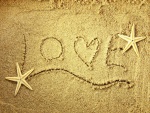 Love escrito en la arena junto a dos estrellas de mar