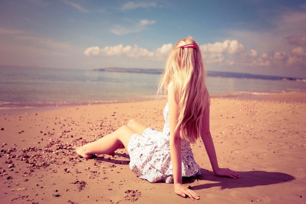 Chica sentada en una playa observando el mar