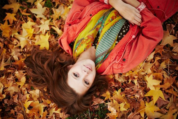 Chica tumbada sobre hojas otoñales