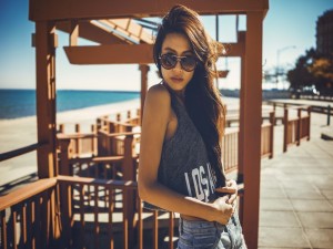 Una chica con gafas de sol junto a una playa